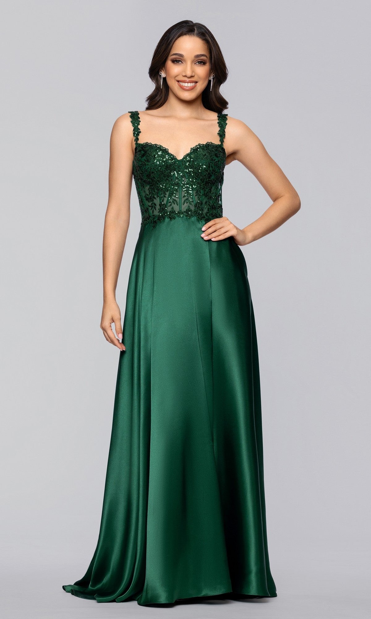A woman wears the Blondie Nites 6088BN long prom dress in hunter, featuring an a-line satin silhouette with a sequin embellished bodice and floor-length skirt, set against a plain light gray background.